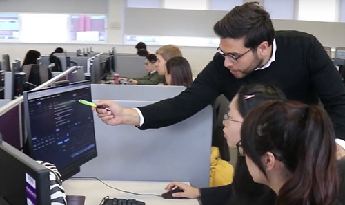 A tutor helping students at a computer