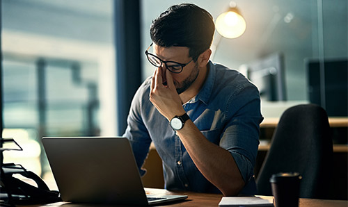 A man looking stressed at a laptop